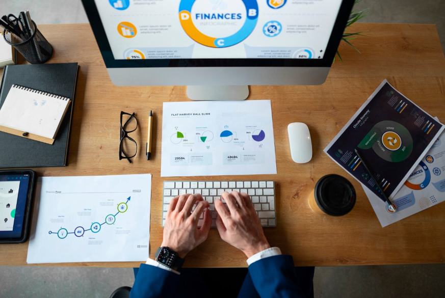 desk setup with charts and a computer illustrating a money management system for tracking finances