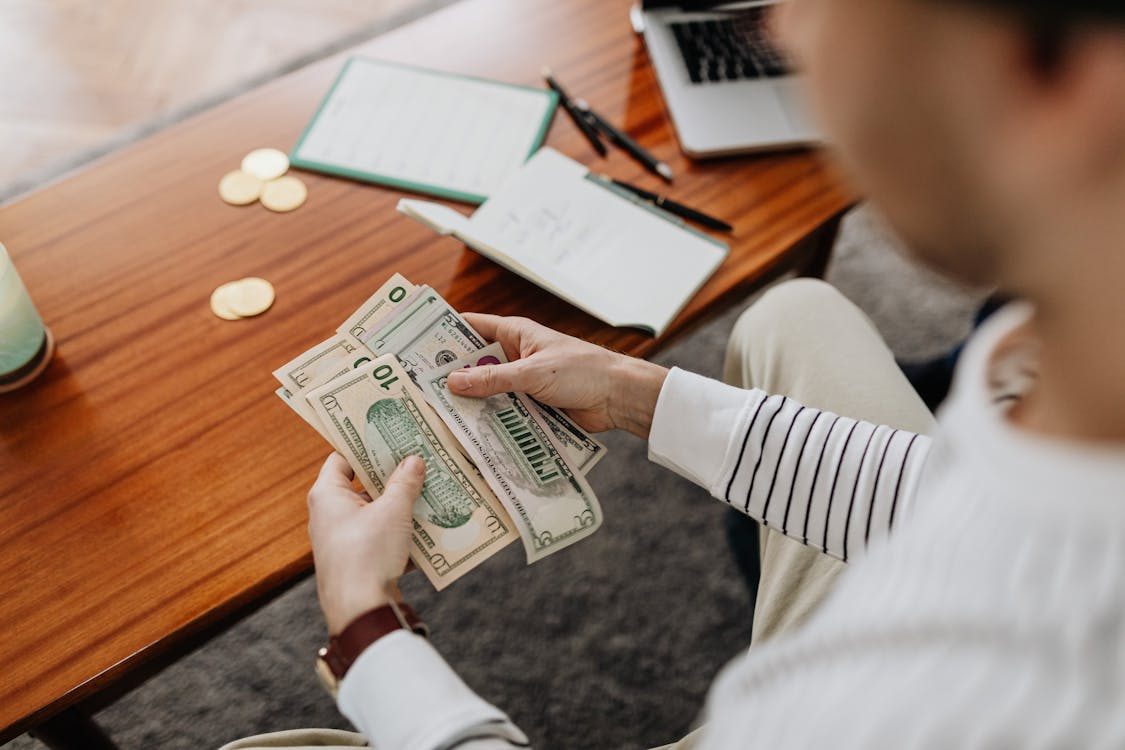 person counting cash near a notebook to illustrate healthy money mindset habits and financial decision-making
