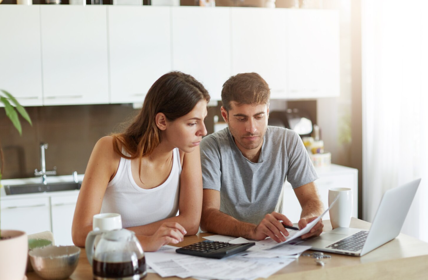 Couple working on financial life planning with bills calculator and laptop