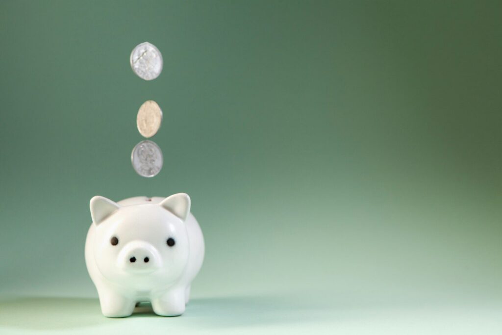 Coins falling into a white piggy bank.